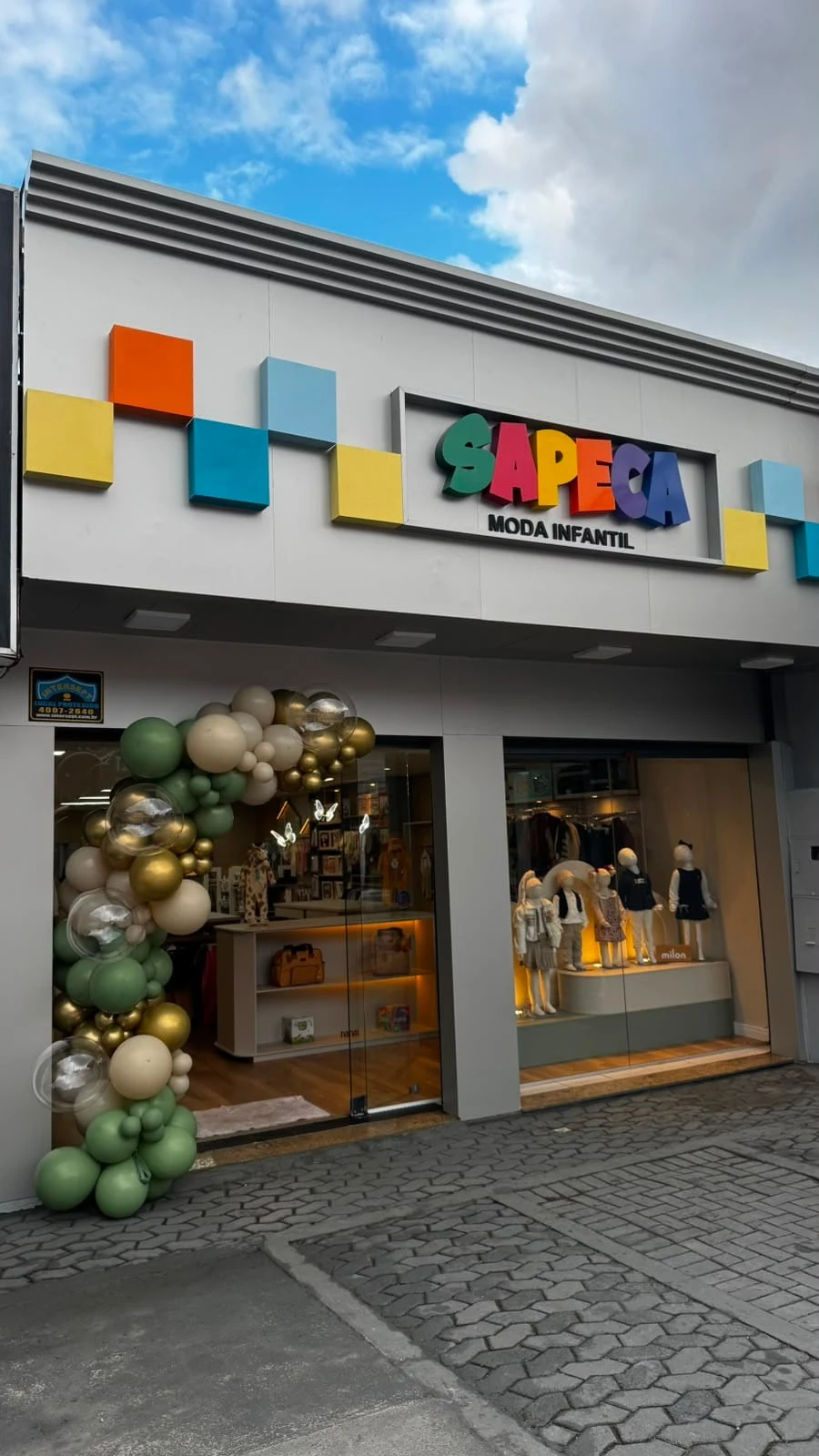 Fachada da nova loja da Sapeca no Bacacheri, com os blocos coloridos, o letreiro e o arco de balões da inauguração